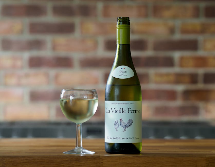 Elegant shot of La Vieille Ferme white wine bottle with glass against brick wall.