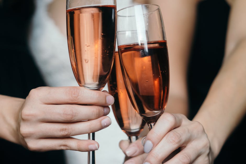 Close-up of hands toasting with rose wine glasses, capturing festive spirit.
